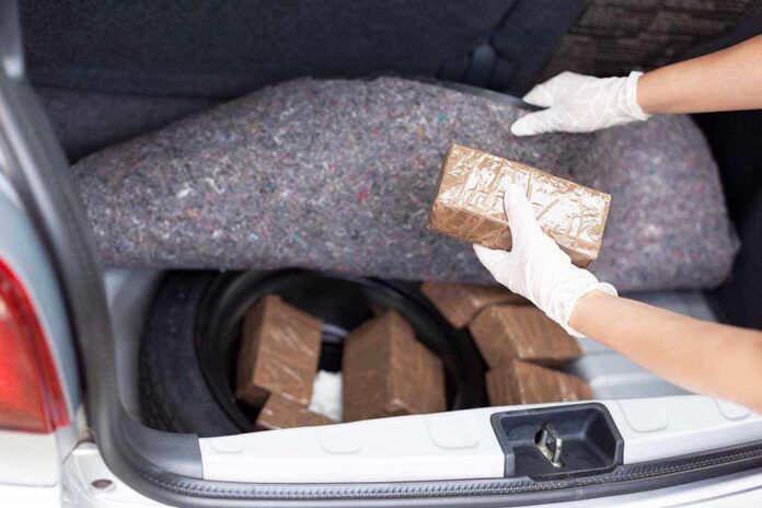 Police,Officer,Holding,Drug,Package,Discovered,In,The,Trunk,Of