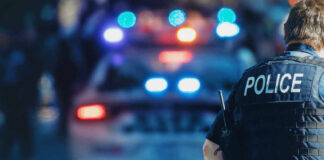 Police officer and vehicle with flashing lights.