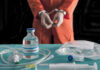 Handcuffed person in orange suit with lethal injection supplies.