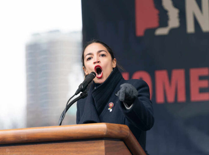 shutterstock_1289128282.jpg featured image Alexandria Ocasio-Cortez passionately speaking at a podium outside.