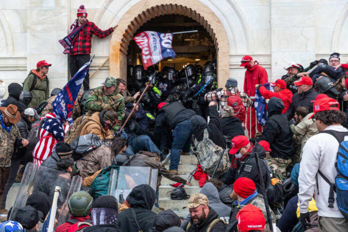 shutterstock_1889190778-1.jpg featured image Crowd storming a building entrance wearing Trump merchandise.