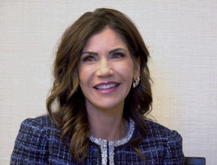 shutterstock_19625176871.jpg featured image Kristi Noem in black and white checkered jacket.