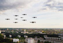 Drones flying over a cityscape under cloudy sky.