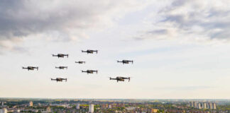 Drones flying over a cityscape under cloudy sky.
