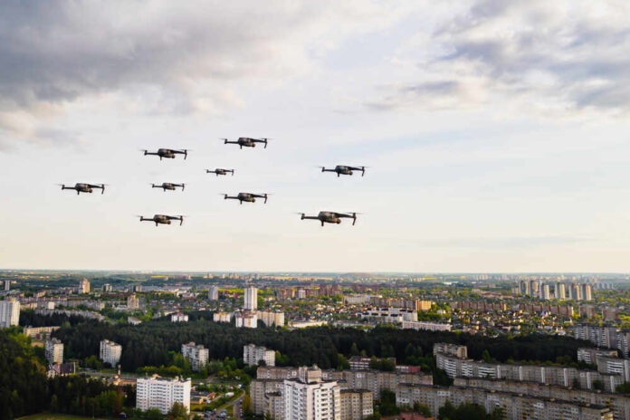 shutterstock_1839955201.jpg featured image Drones flying over a cityscape under cloudy sky.