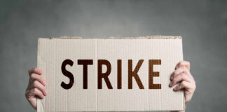 Two hands holding cardboard sign with strike text