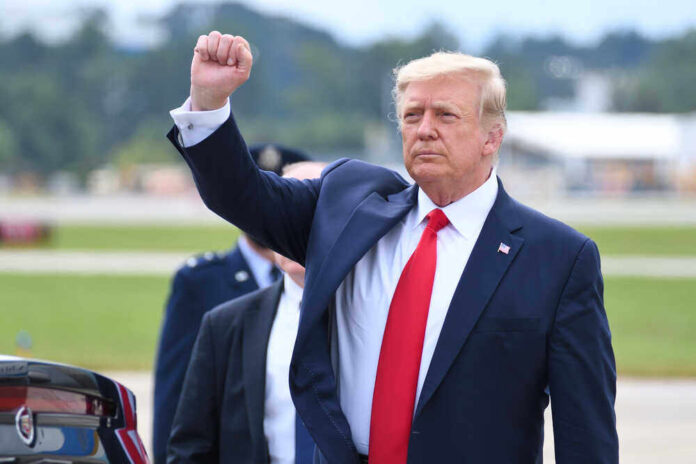 shutterstock_1821865592.jpg featured image Donald Trump raising their arm in a fist gesture near a car.