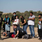 Group of people talking to border patrol officer.