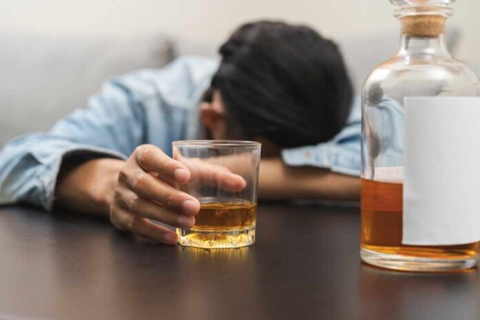 shutterstock_2474121053.jpg featured image Person asleep at table holding drink glass