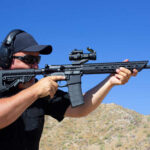 AR-15 Person aiming a rifle outdoors wearing ear protection