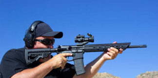 AR-15 Person aiming a rifle outdoors wearing ear protection