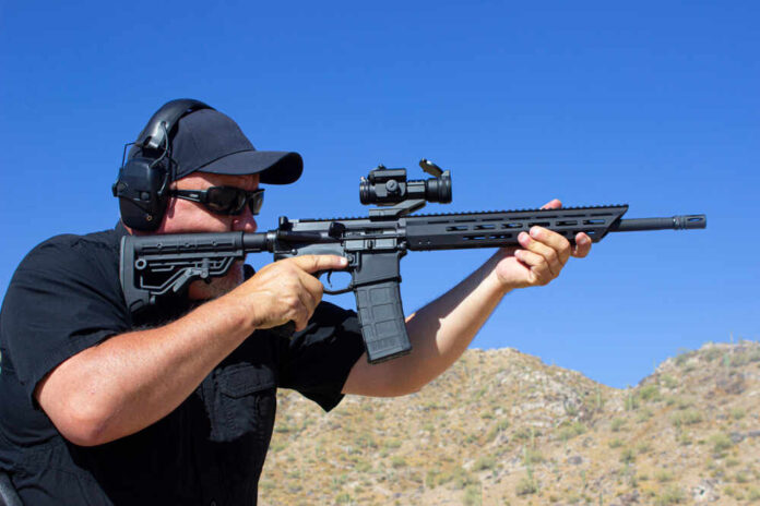 shutterstock_1577703415.jpg featured image AR-15 Person aiming a rifle outdoors wearing ear protection
