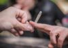 Hands passing a lit joint outdoors.