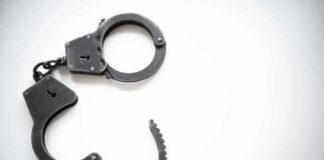 Open metal handcuffs on white background.