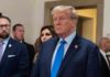 Donald Trump in formal attire standing indoors.