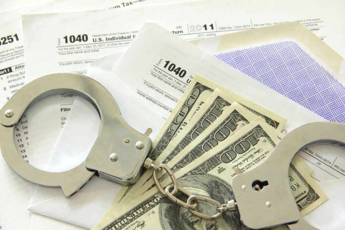shutterstock_106939859.jpg Handcuffs, dollar bills, and tax forms on a table.