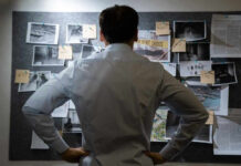 Man examining investigation board with photos and notes