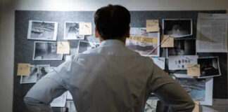 Man examining investigation board with photos and notes