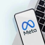 Meta logo on smartphone next to laptop keyboard