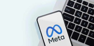 Meta logo on smartphone next to laptop keyboard