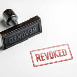 Wooden stamp next to red revoked text stamp