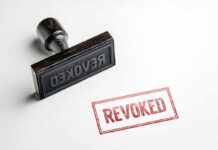 Wooden stamp next to red revoked text stamp