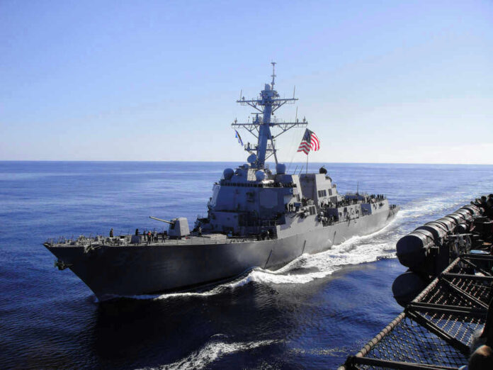 shutterstock_1250591794.jpg Warship with American flag sailing in the ocean.