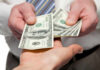 Two hands exchanging cash bills