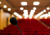 Microphone in focus, blurred audience seats and lights.