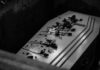 Coffin with flowers inside a dark burial plot