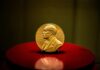A gold Nobel Prize medal displayed on a red pedestal