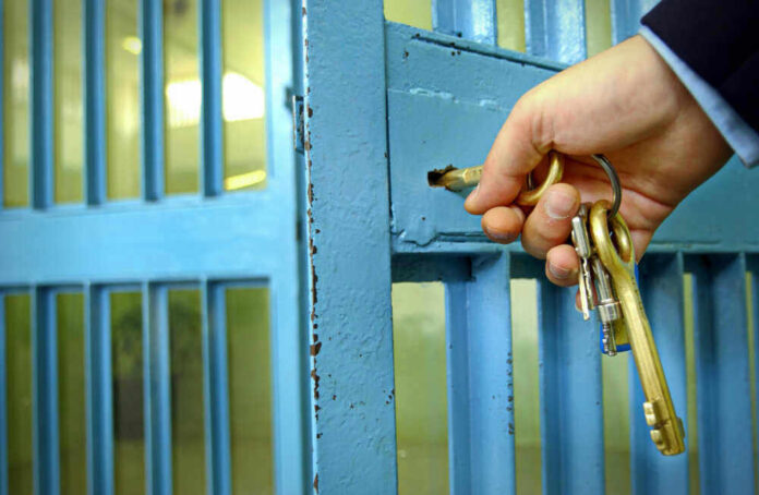 Hand unlocking blue metal door with keys