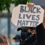 Person holding Black Lives Matter sign at protest.