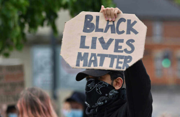 Person holding Black Lives Matter sign at protest.