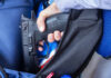 A hand holding a gun inside a backpack