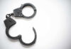 Open metal handcuffs on white background.