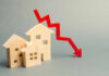 Wooden model houses with a red downward trend arrow
