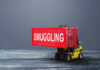 A toy forklift carrying a red shipping container labeled 'SMUGGLING'