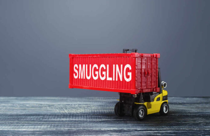A toy forklift carrying a red shipping container labeled 'SMUGGLING'