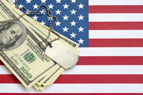 A stack of dollar bills on an American flag with a military dog tag