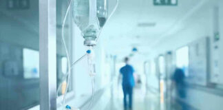 Hospital corridor with IV drip and healthcare worker.