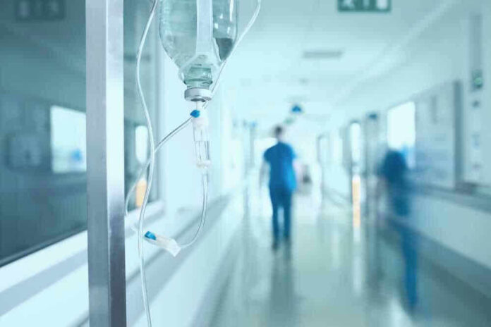 Hospital corridor with IV drip and healthcare worker.
