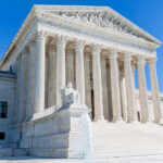 Supreme Court building with columns, fountain, and statue.