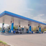 A modern gas station with fuel pumps and parked vehicles