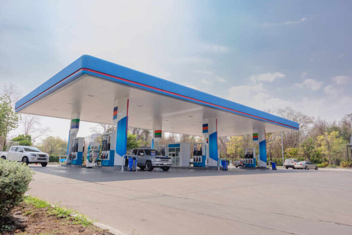 A modern gas station with fuel pumps and parked vehicles