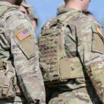 Soldiers in camouflage uniforms with American flag patches.
