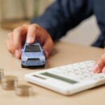 Person calculating expenses with a toy car and coins on the table