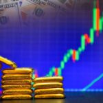 Hand placing gold bars next to a financial graph and dollar bills