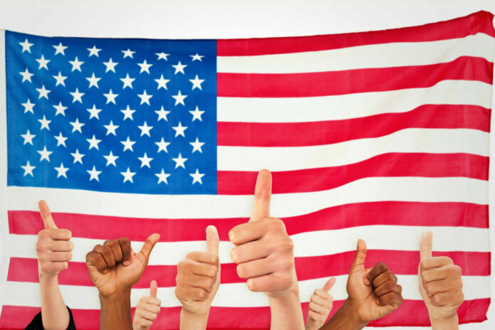 shutterstock_291761663.jpg Thumbs up in front of American flag.