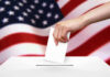 Hand dropping ballot into box, American flag background.